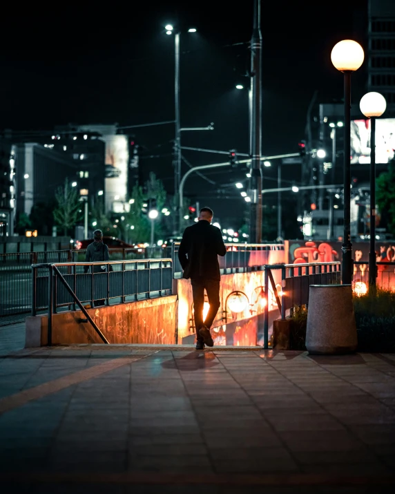 a man standing on the sidewalk next to a railing with his bike