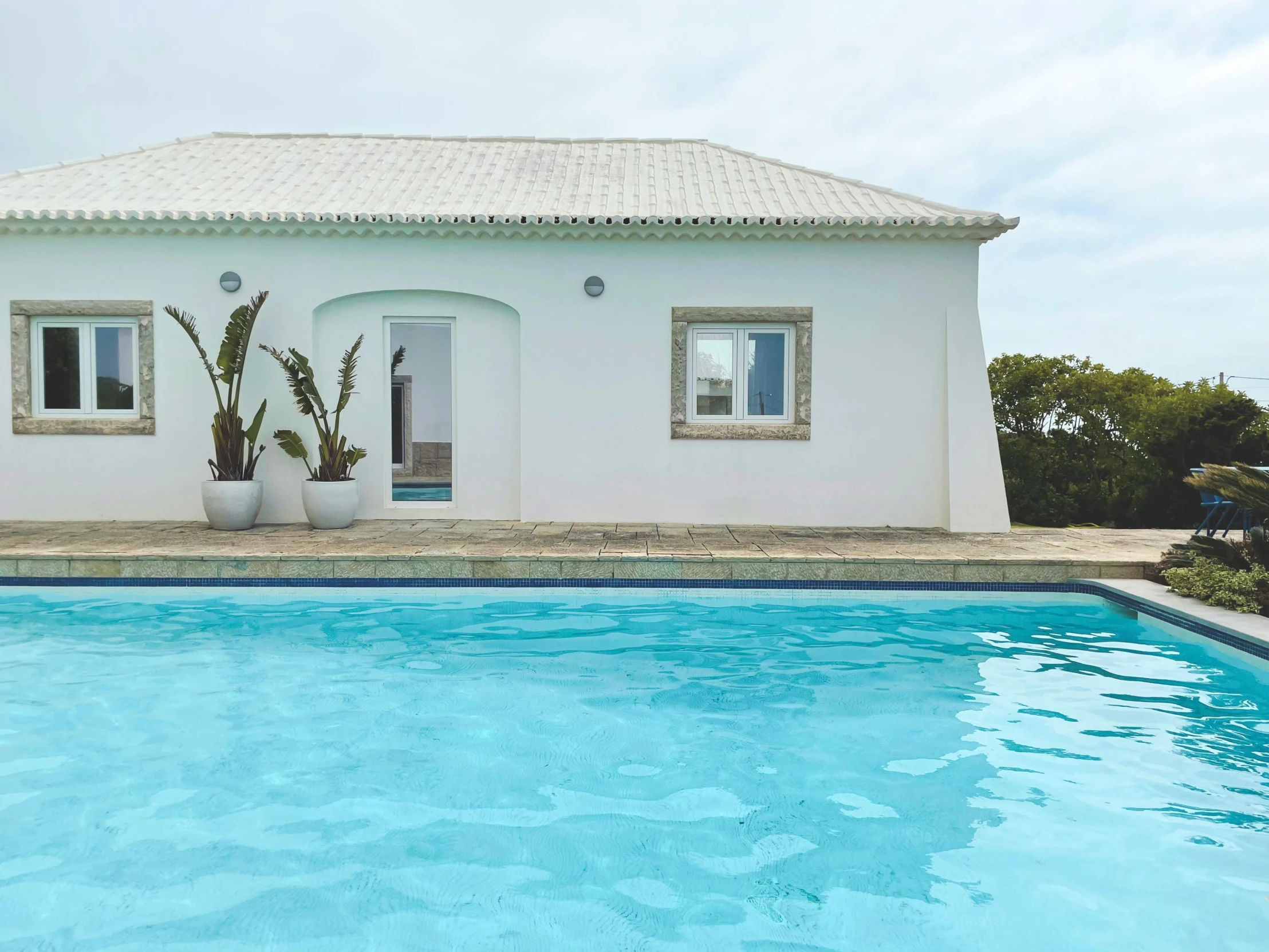 an exterior view of a white house, with a swimming pool