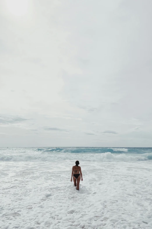 a person walking through the shallows on a beach