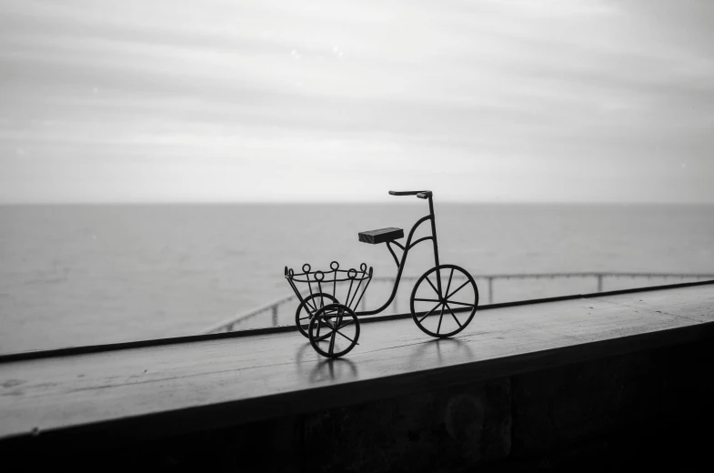 a small, bicycle is sitting on the ledge by the water