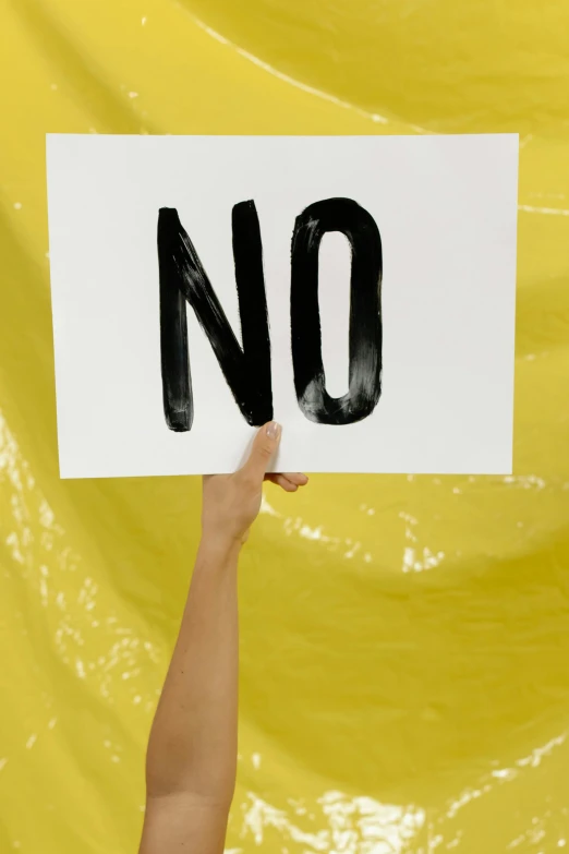 a hand holds up a sign with the word no