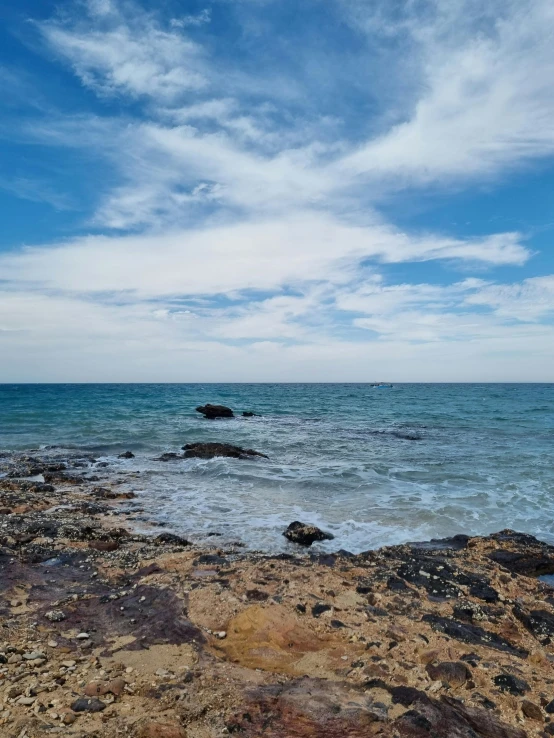 a lone surfboard sitting on a rocky beach