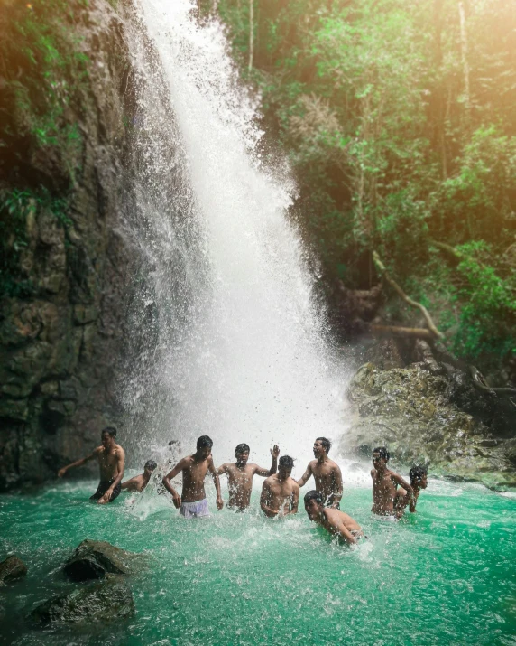 a group of men standing in the water at a waterfall