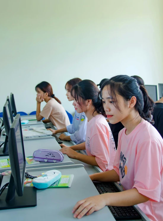 several people in pink shirts are sitting at a long table