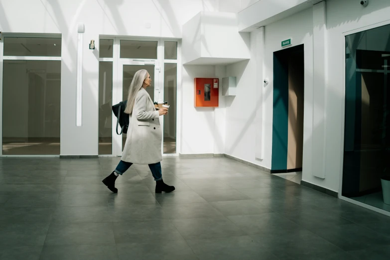 a woman walking in a building while looking at her cell phone