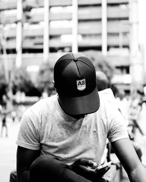 black and white pograph of man sitting on a bench with an iphone