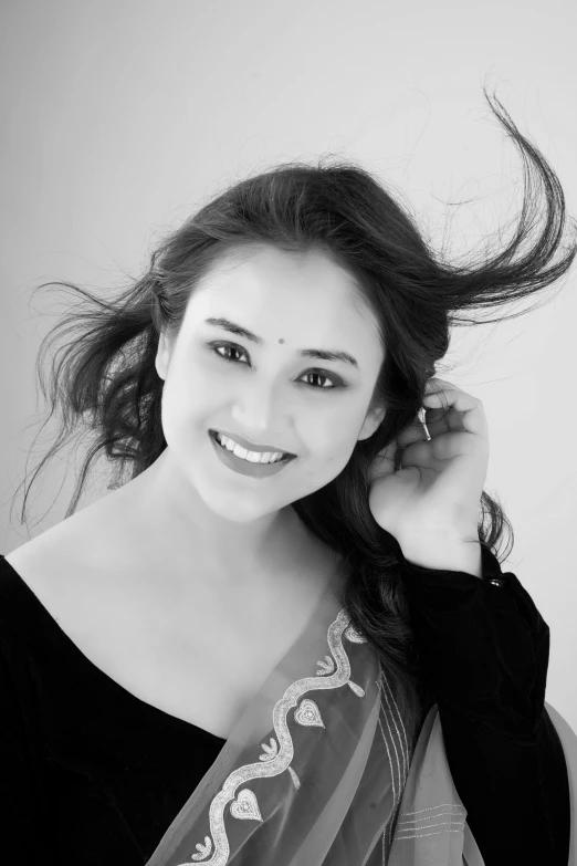 a woman with very long hair smiles as she holds her ponytail up