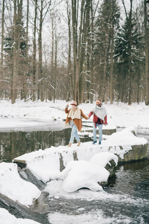 a couple of people standing on top of a bridge over snow covered ground