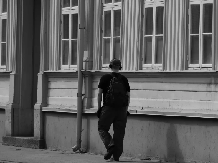 a man is walking down the sidewalk, while looking at a building