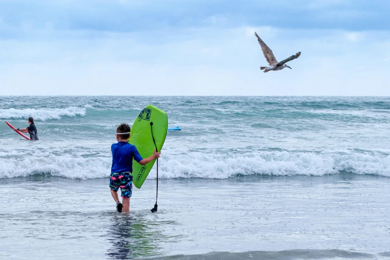 the people are playing on the beach while one surfer is swimming