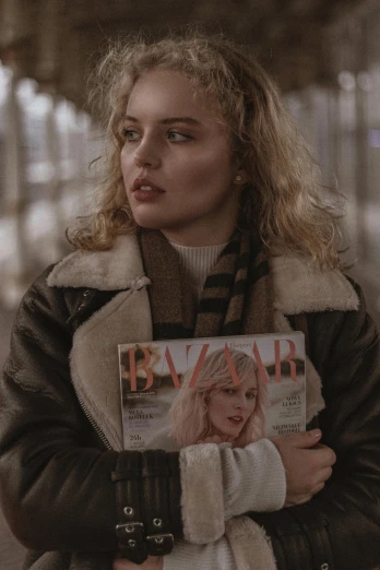 a woman in winter clothes holding up a magazine
