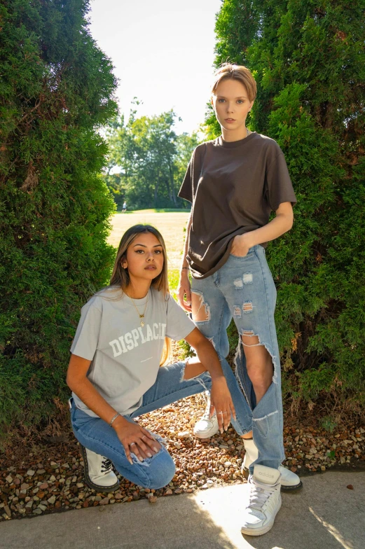 two women posing in front of some bushes