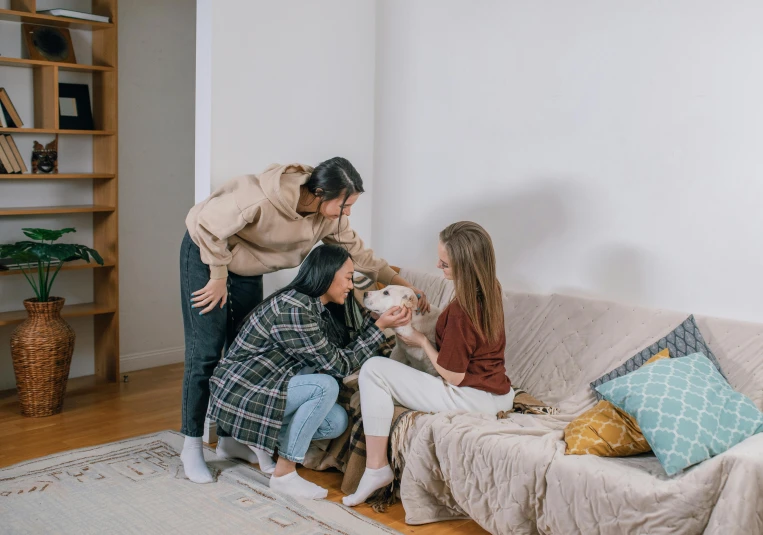 three women in a living room hanging out with two of them holding an infant