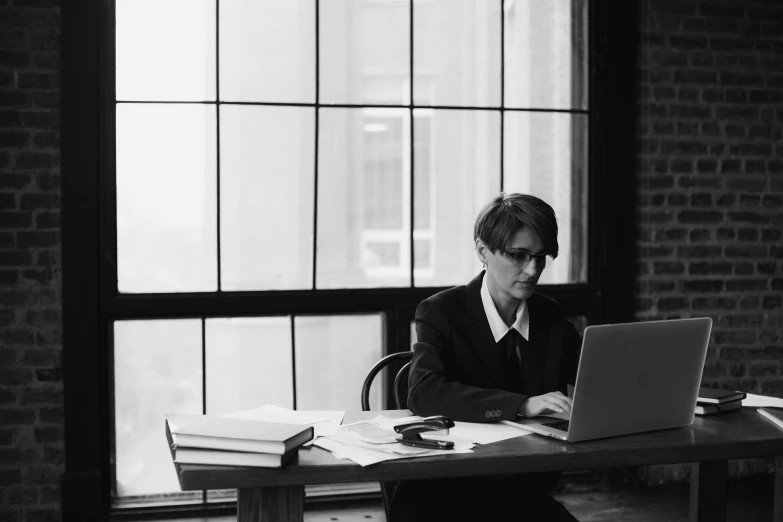 a person sitting in a chair at a desk working on a laptop