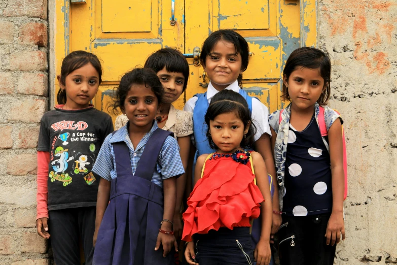 a group of children standing next to each other in front of a yellow door