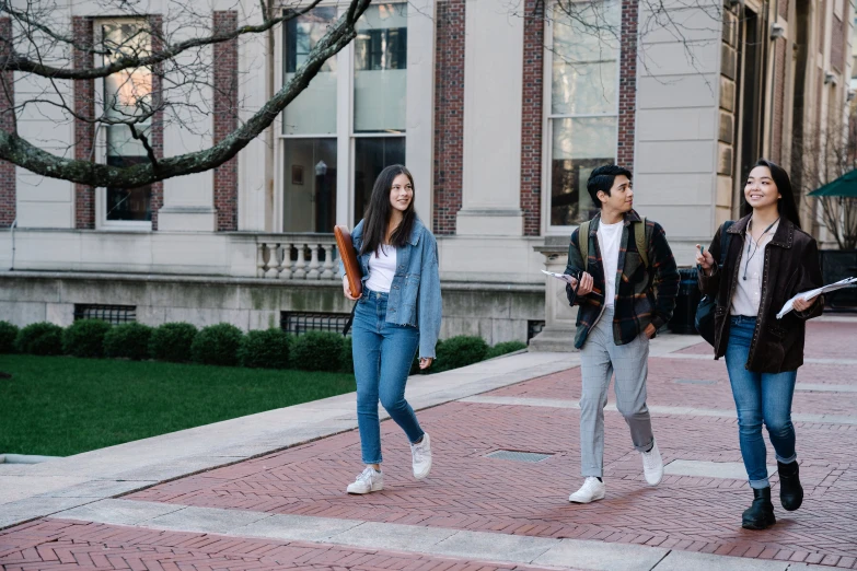 two girls and a boy walk down a sidewalk