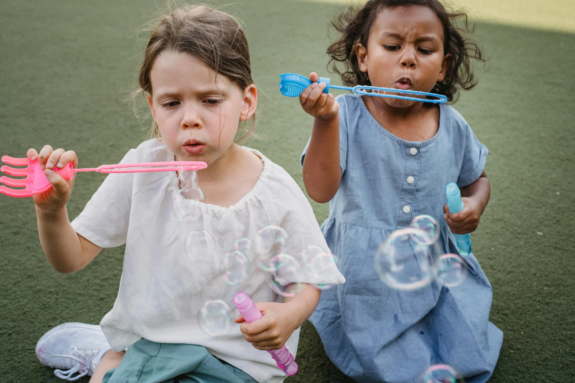 two children are playing with bubbles in the park