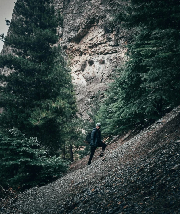 there is a person walking up a trail by a mountain