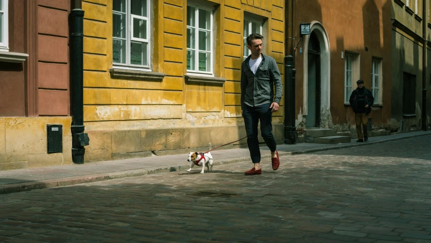 man walking his dog down a cobble stone street