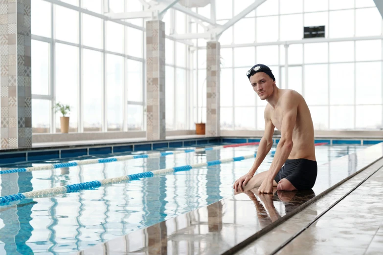 a young man is sitting in the middle of a swimming pool