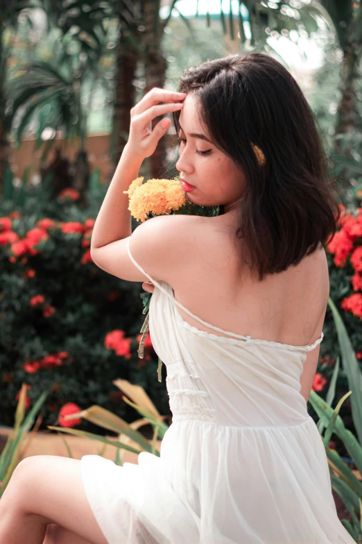 a woman sitting on a bench holding yellow and white flowers