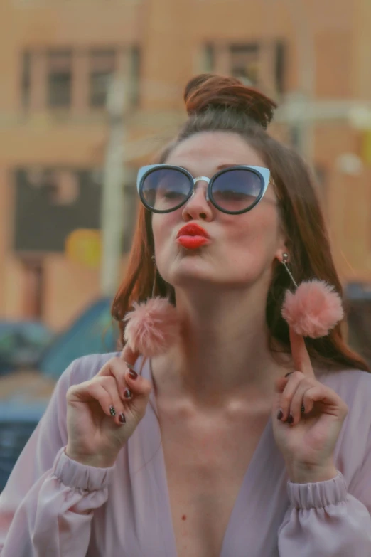 a woman in a pink top blowing a bubble with red lipstick