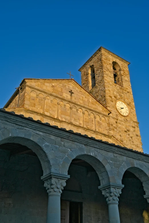a clock tower at dusk behind some stone pillars