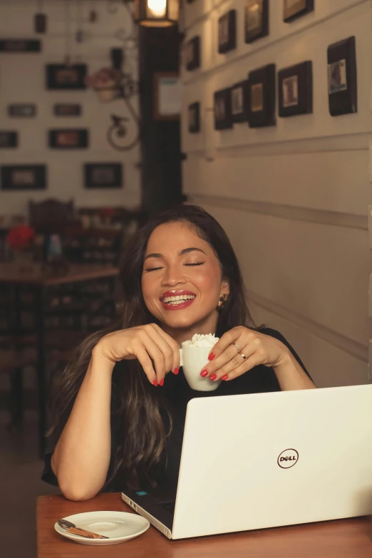 smiling woman with closed eyes, with laptop computer, in restaurant