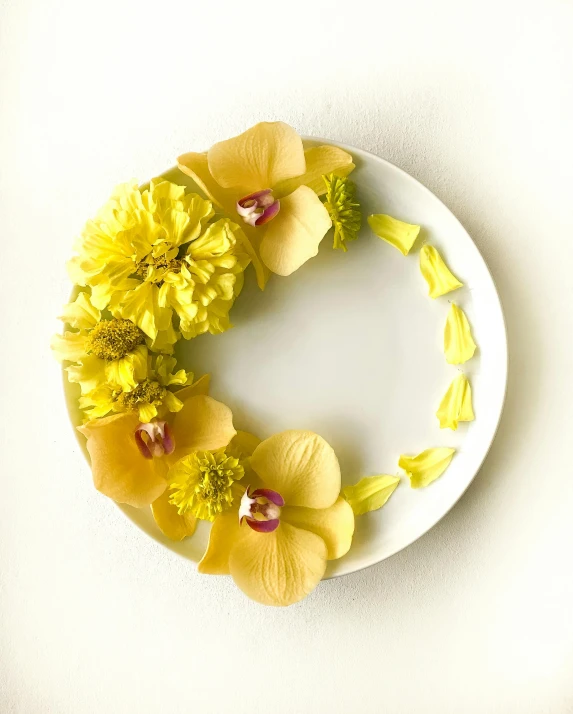 a white plate topped with yellow flowers and grass