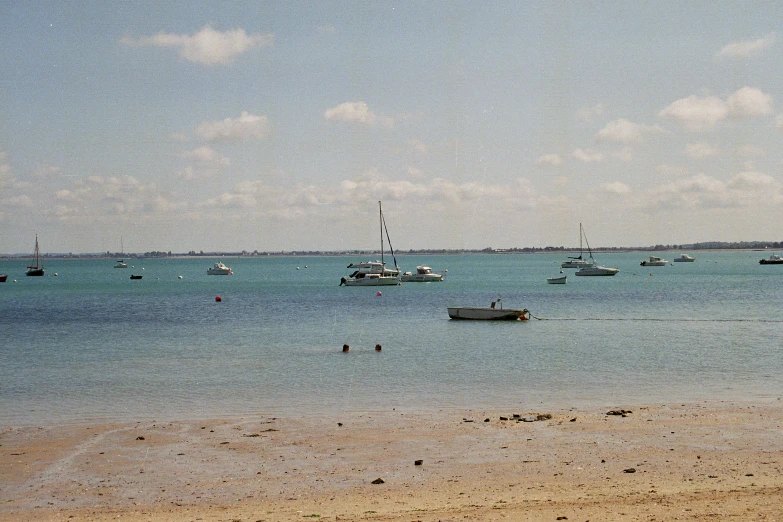 several boats floating on top of the ocean near shore