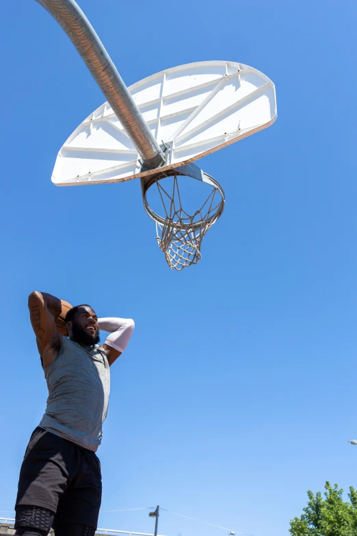 a man stands near a basketball going in a hoop