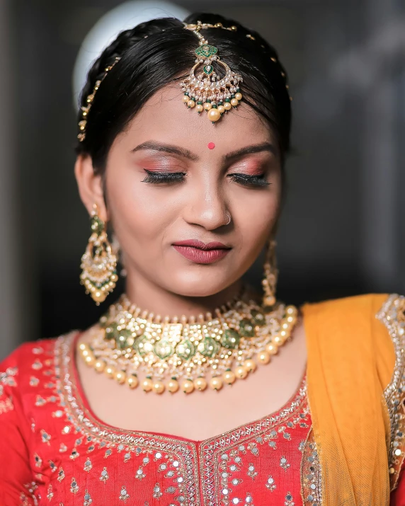 a woman wearing a gold necklace with an orange top