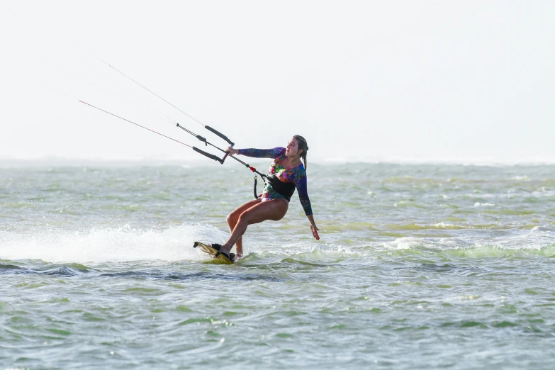 a woman holding onto a kite as she wind surfs in the ocean