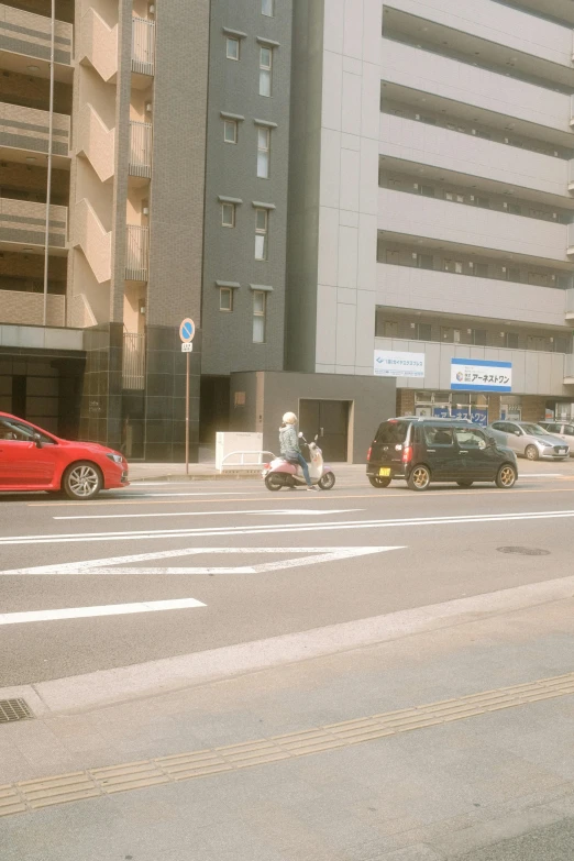 two motorcycles driving down the street near buildings