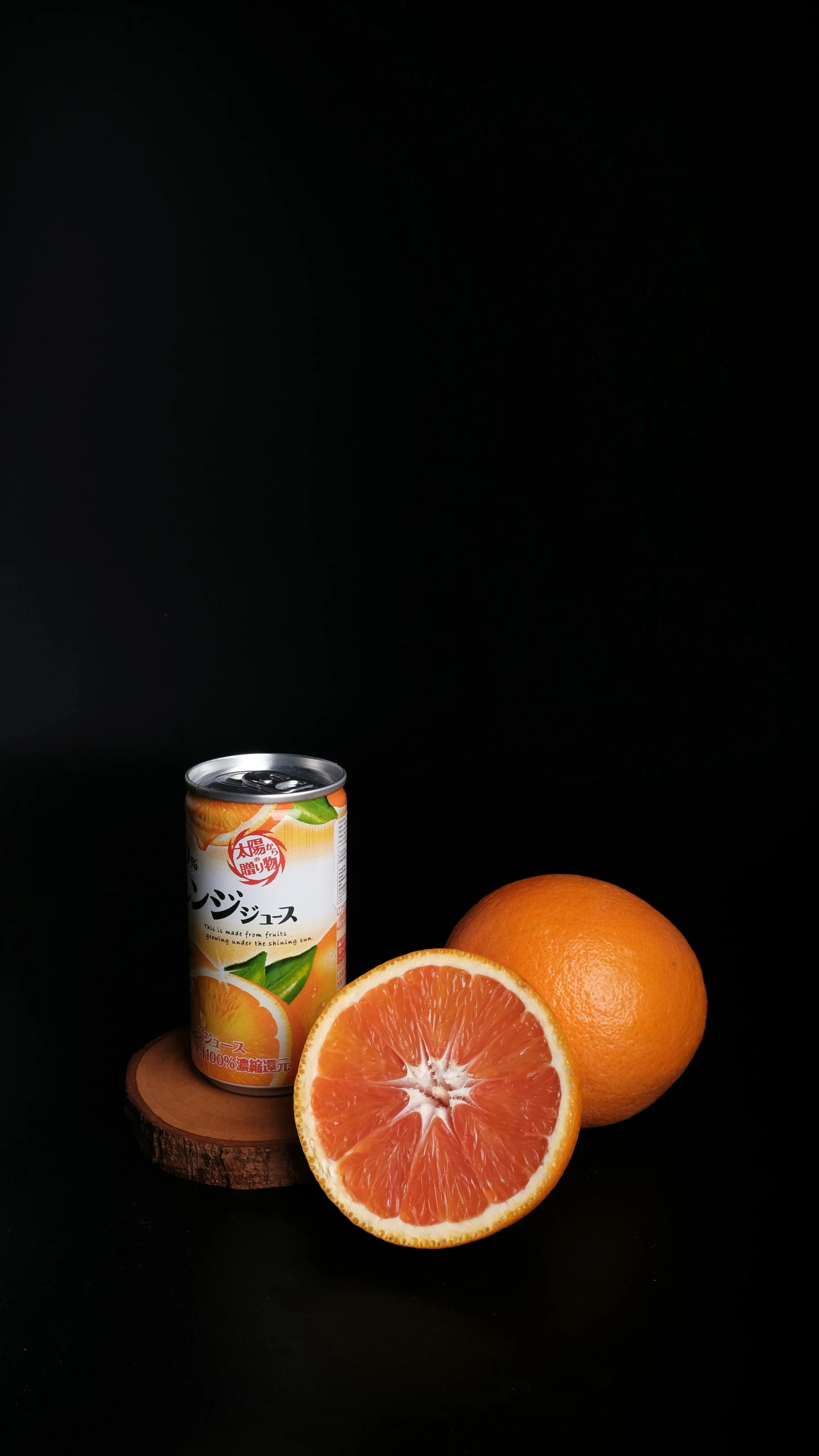 a can and half a gfruit sitting on a wooden coaster