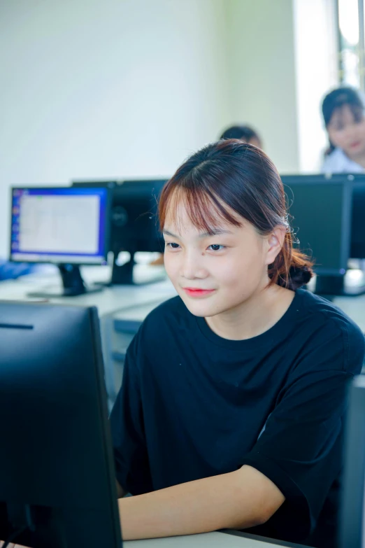 a girl sitting in front of a computer desk