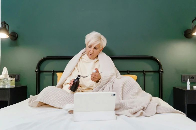 an older woman is sitting on her bed using her computer