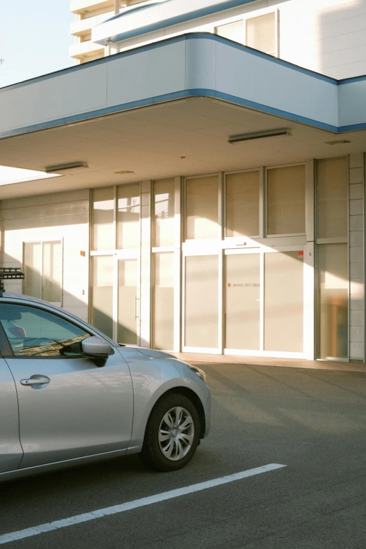 a small silver car is parked in front of a white building