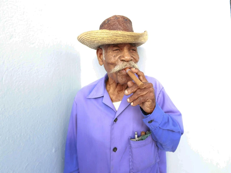 a man with a hat on holding a cigarette