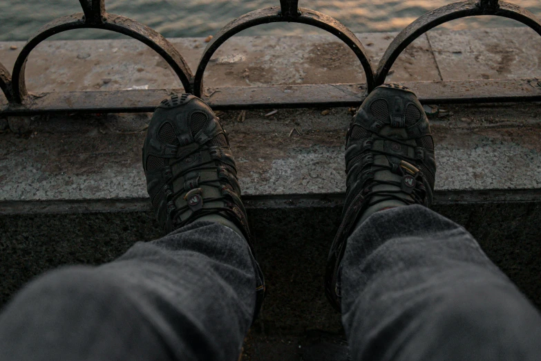 the legs of someone standing in front of some water