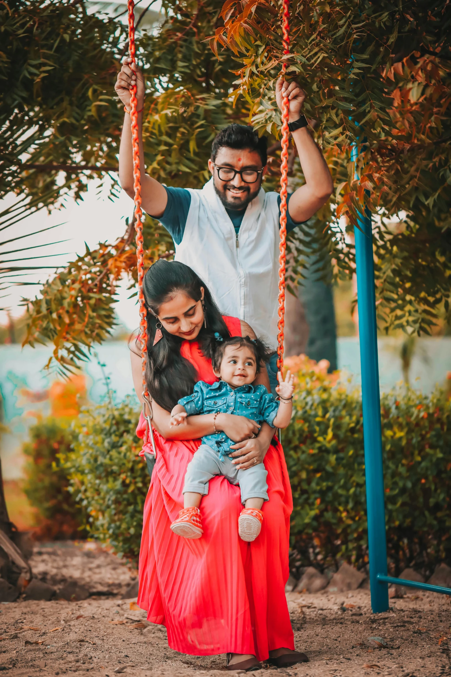 a couple and their child are on a swing together