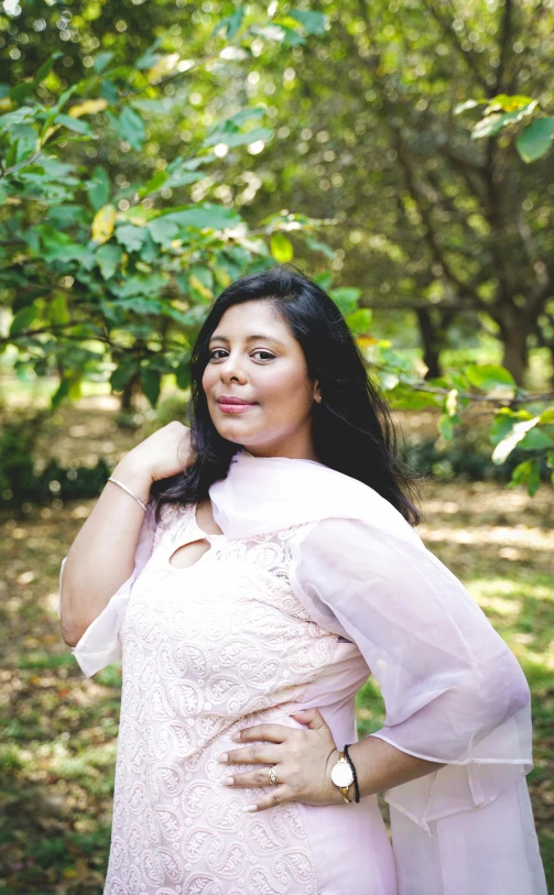 a woman wearing a pink dress poses in a forest