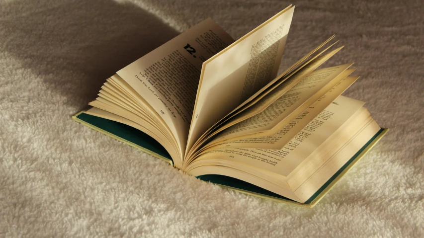 an open book sitting on top of a white blanket