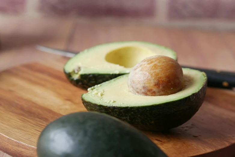 an avocado and a knife on a wooden  board