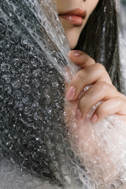 a close - up po of a woman holding her hand out, water flowing over her shoulders and face