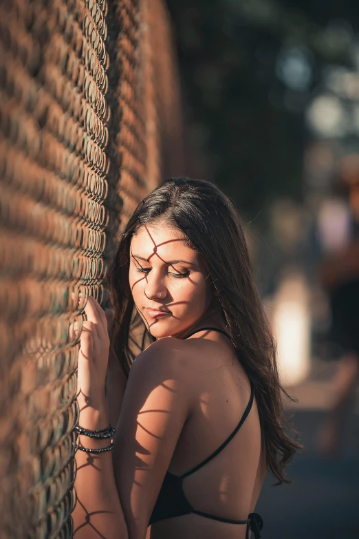 a girl is standing by a fence looking down