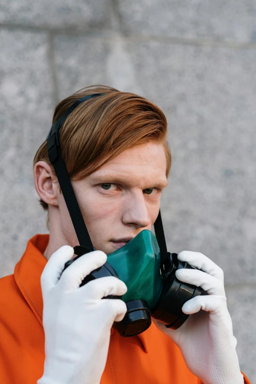 the man is wearing white gloves and a green mask