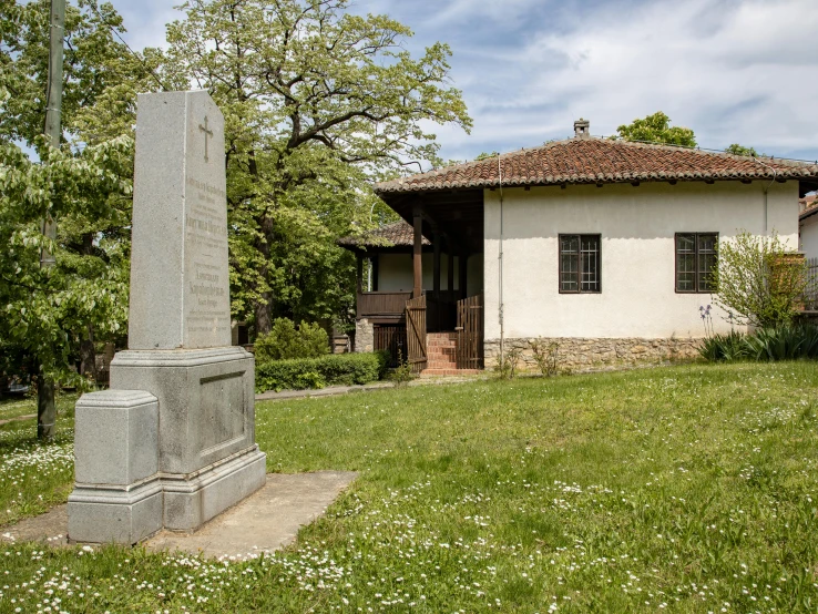 a small white house with an obelisk in the grass