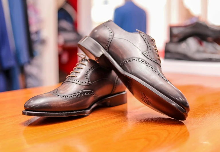 two mens shoes sit side by side on top of a wooden table