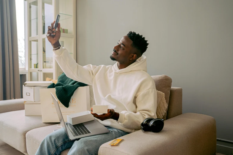 a man sitting on a couch holding two laptop computers